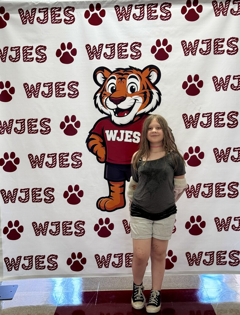 girl standing in front of WJES banner