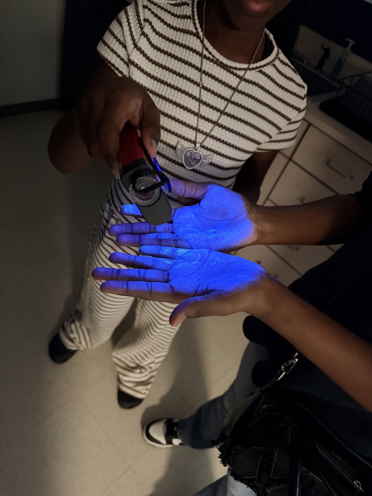 Girls are washing thier hands with blacklight to demonstrate proper handwashing.