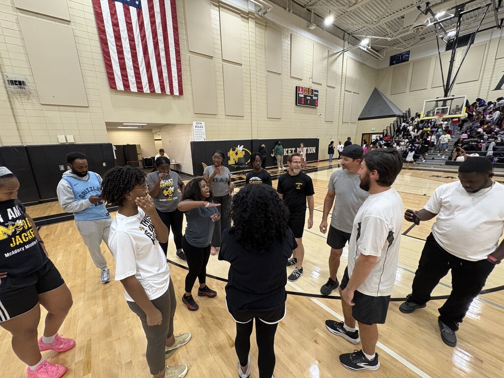 McAdory teachers huddled up on the court with students filling the stands behind them.