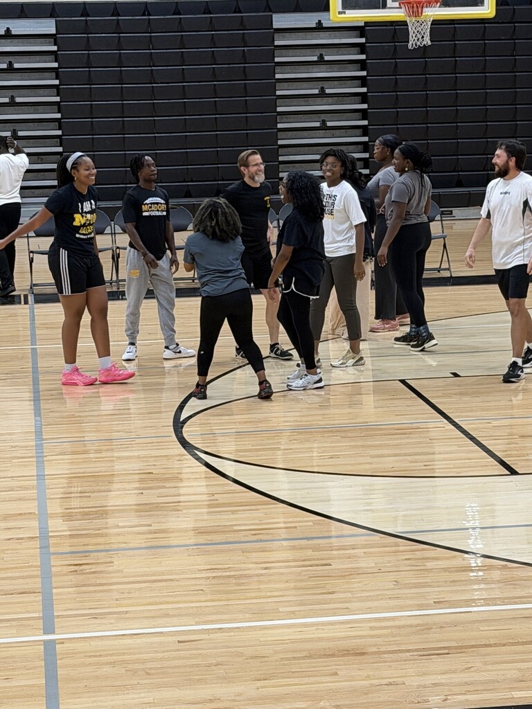 McAdory teachers laughing together on the gym floor before the volleyball game.