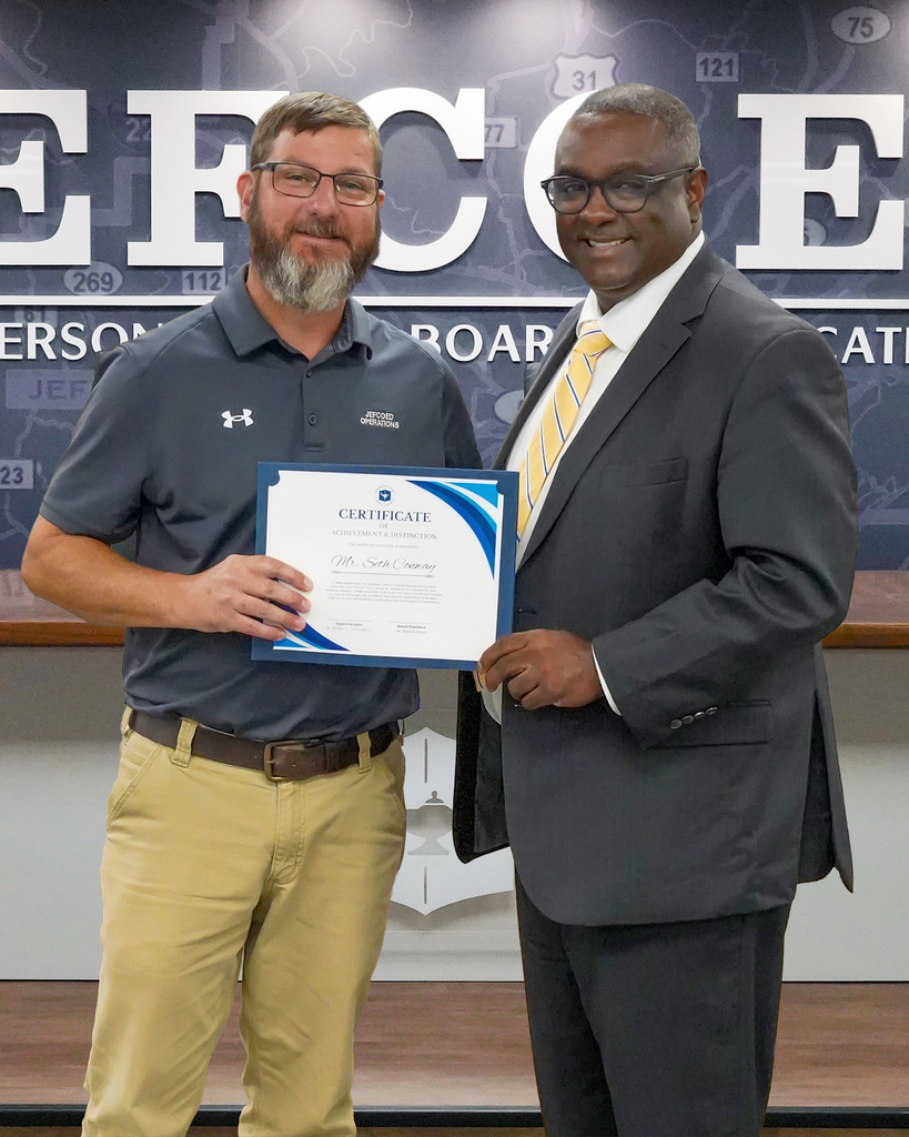 Superintendent Dr. Walter Gonsoulin smiles for a photo with Mr. Seth Conway in the Jefferson County Schools board room.