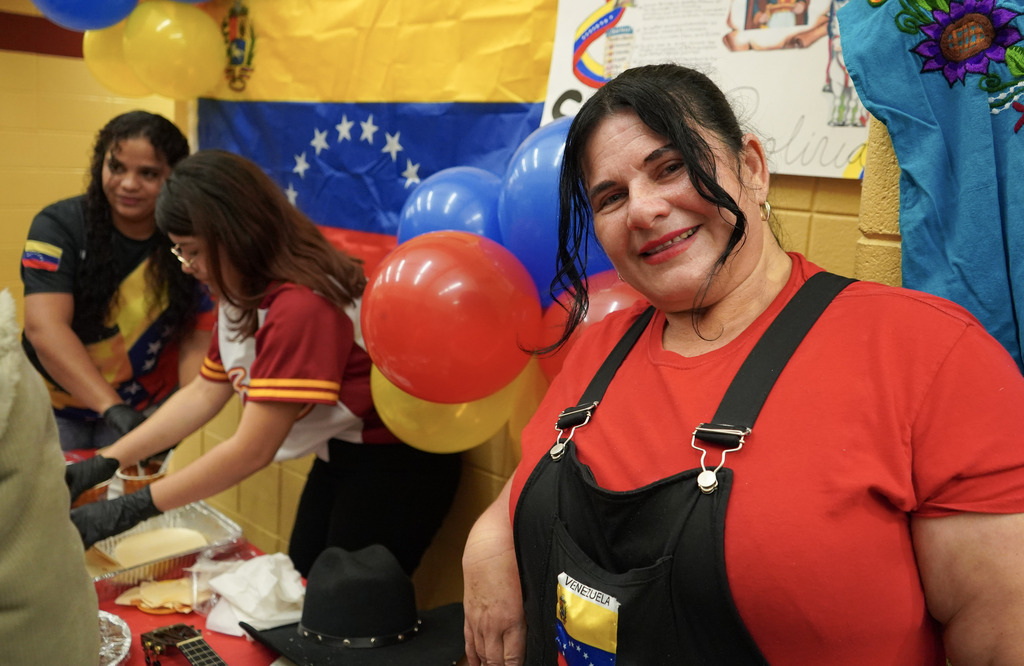 A woman smiles while standing in front of a booth at a Hispanic Heritage Festival.