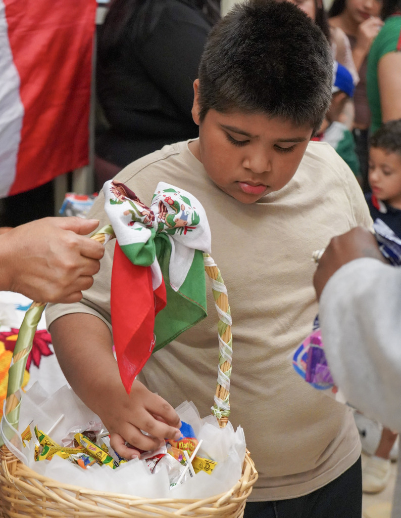 A child grabs a piece of candy out of a basket.