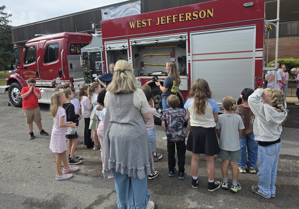 students looking to see what's inside of the compartments on a firetruck