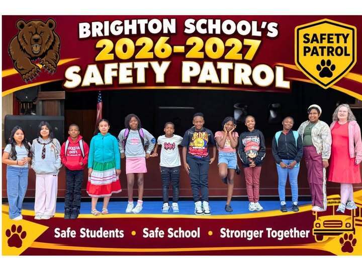 students standing in a line across the front of a school stage smiling