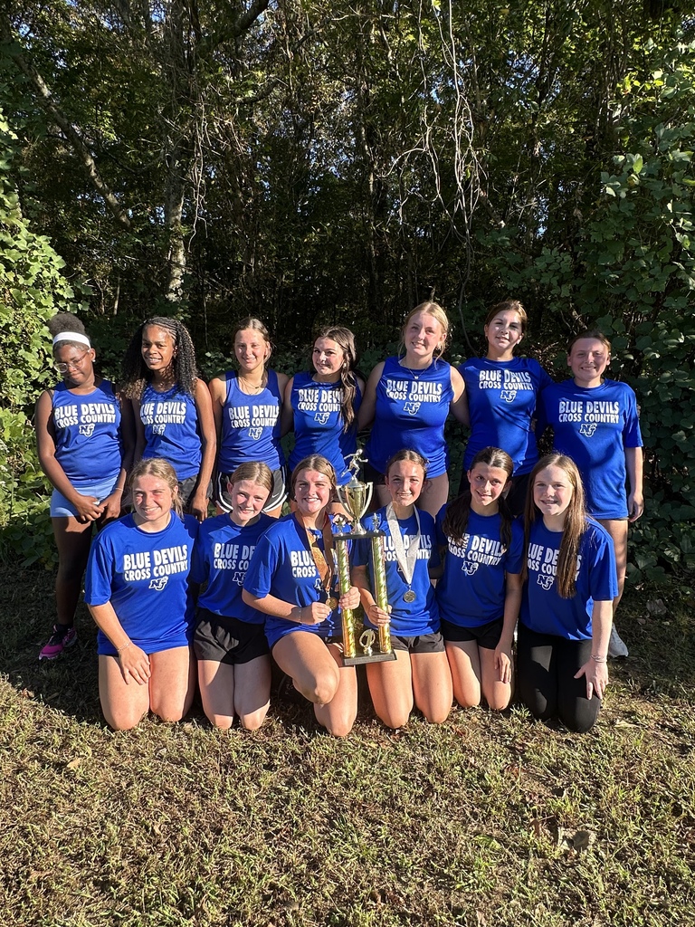 Two rows of the girls cross country team with their trophy.