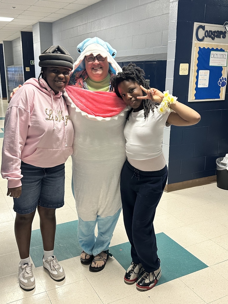 Lady dressed as a shark and hugging two girls 
