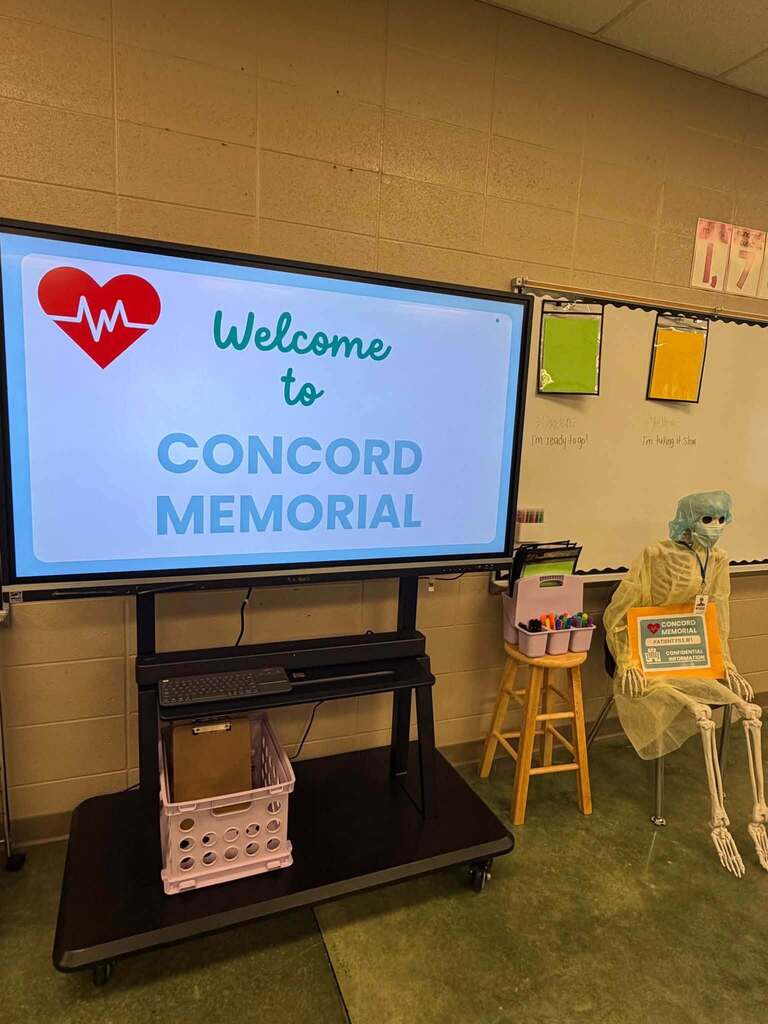 A screen in a classroom says "Welcome to Concord Memorial".