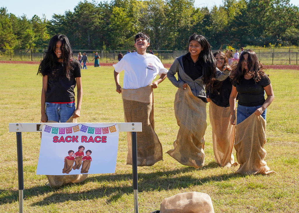 Students participate in sack races outdoors.
