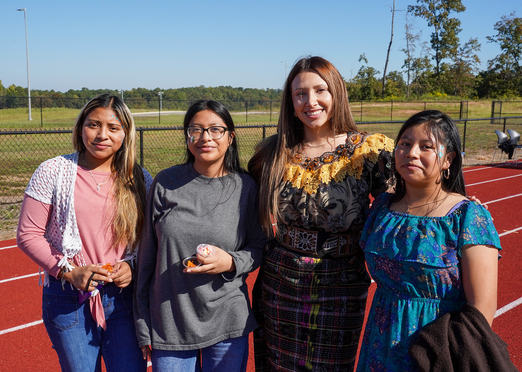 Students smile for a photo while standing on an outdoor track.