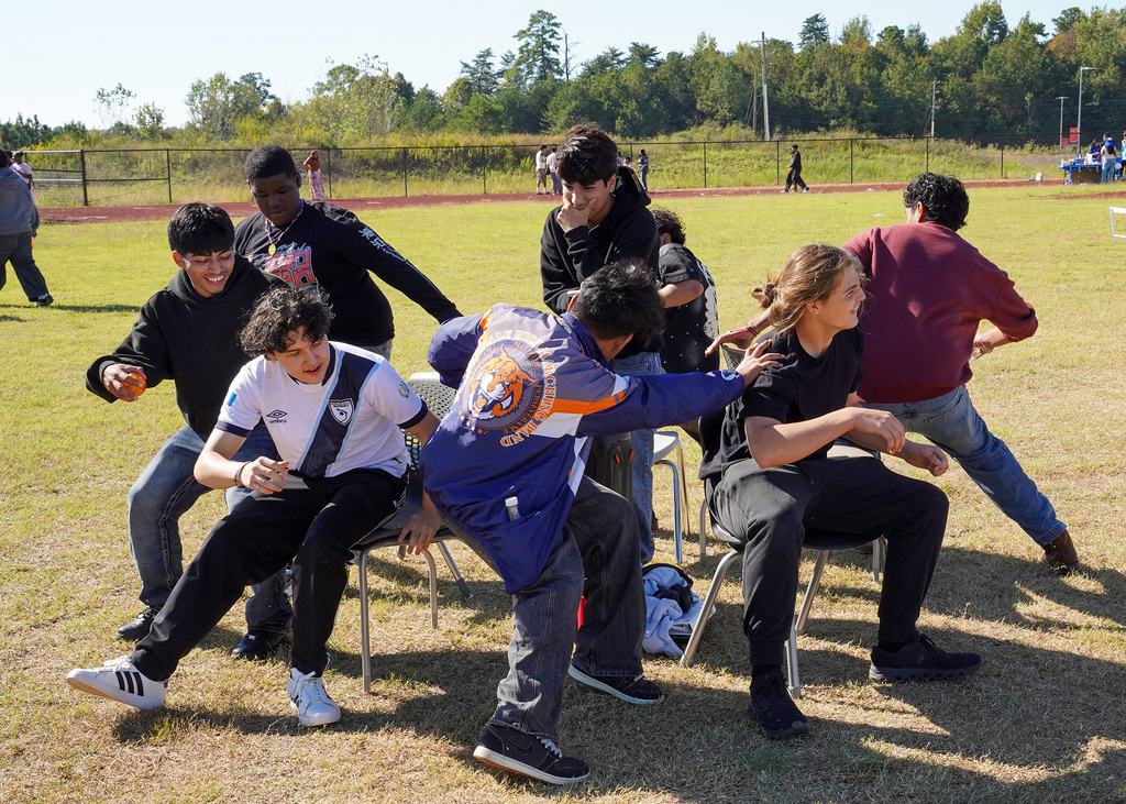 Students smile while playing musical chairs outdoors.