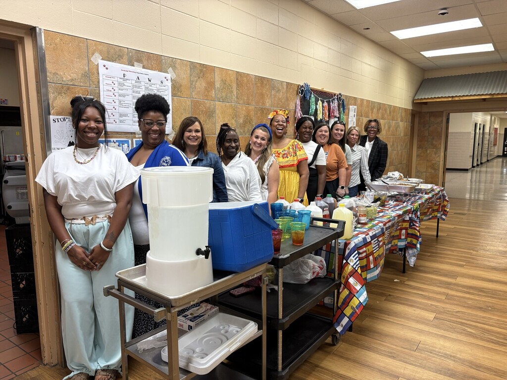 Teachers posing for a picture behind the food service table.
