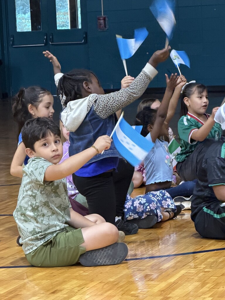 Students sitting and waving Hispanic flags.