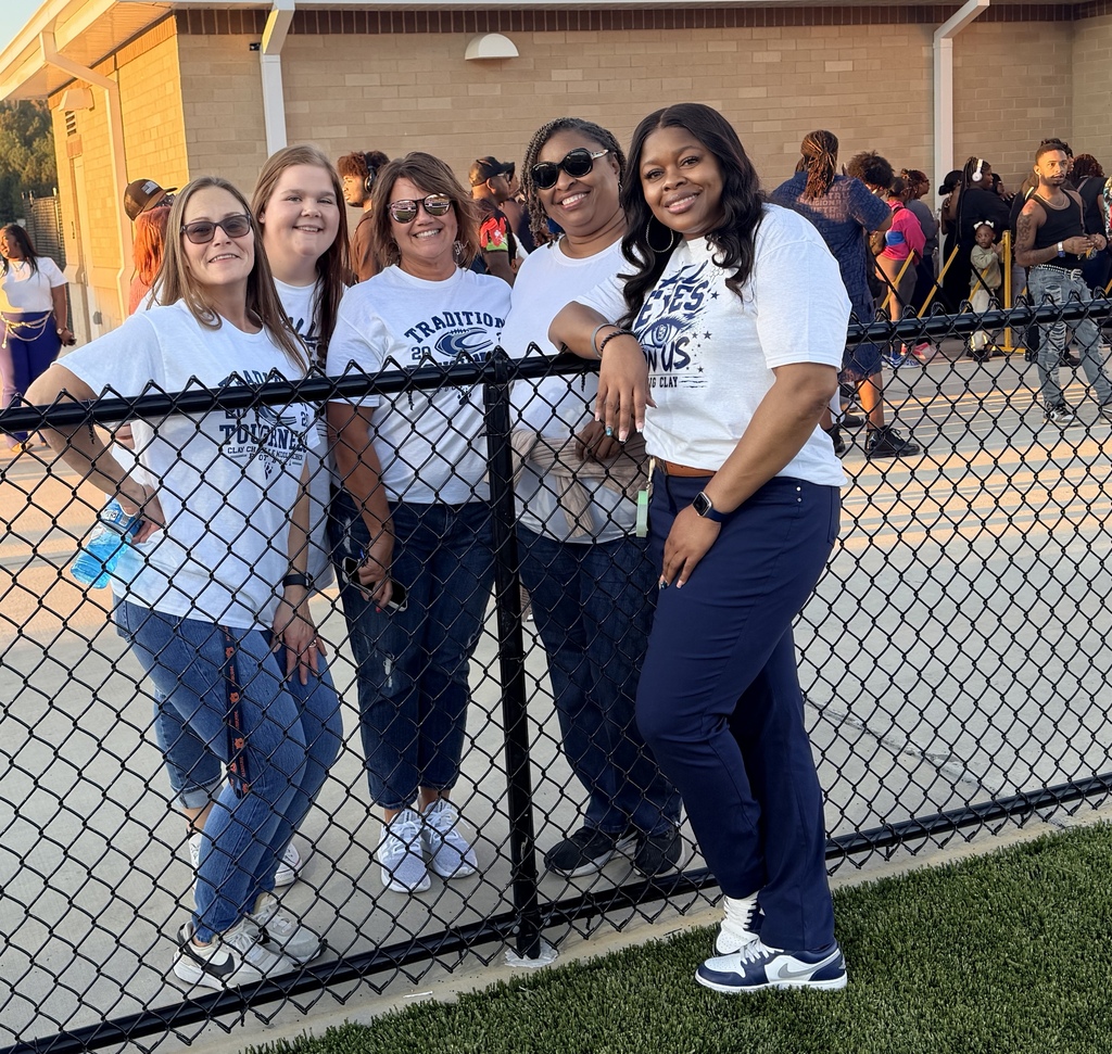Group of women wearing white shirts standing by a fence