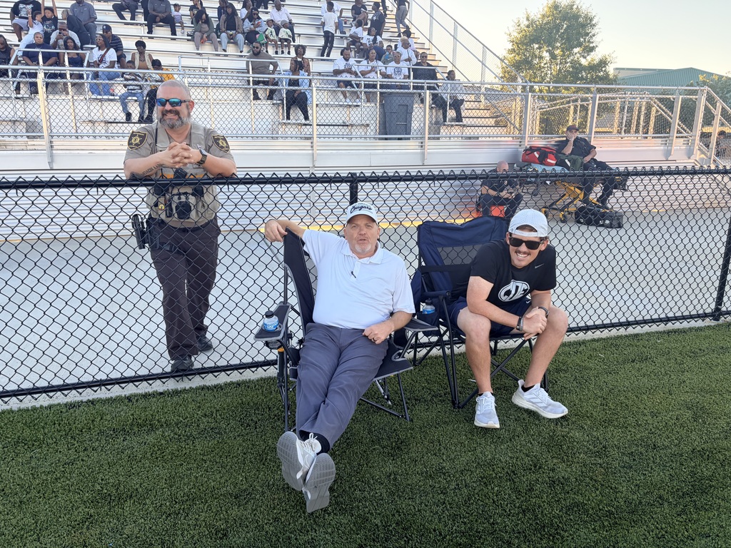 Two men sitting in chairs with a police officer 