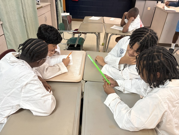 students sitting in desks wearing labcoats