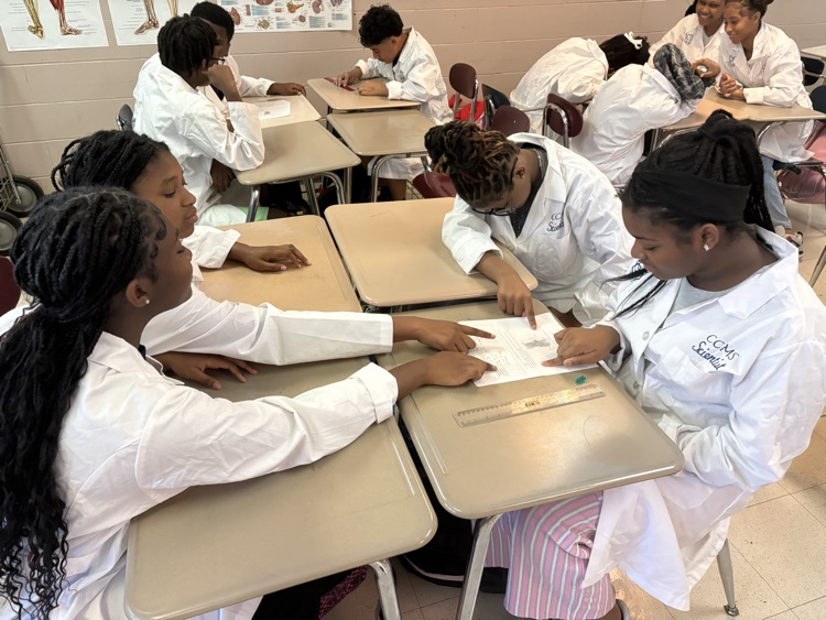 students writting assessments on paper wearing white coats