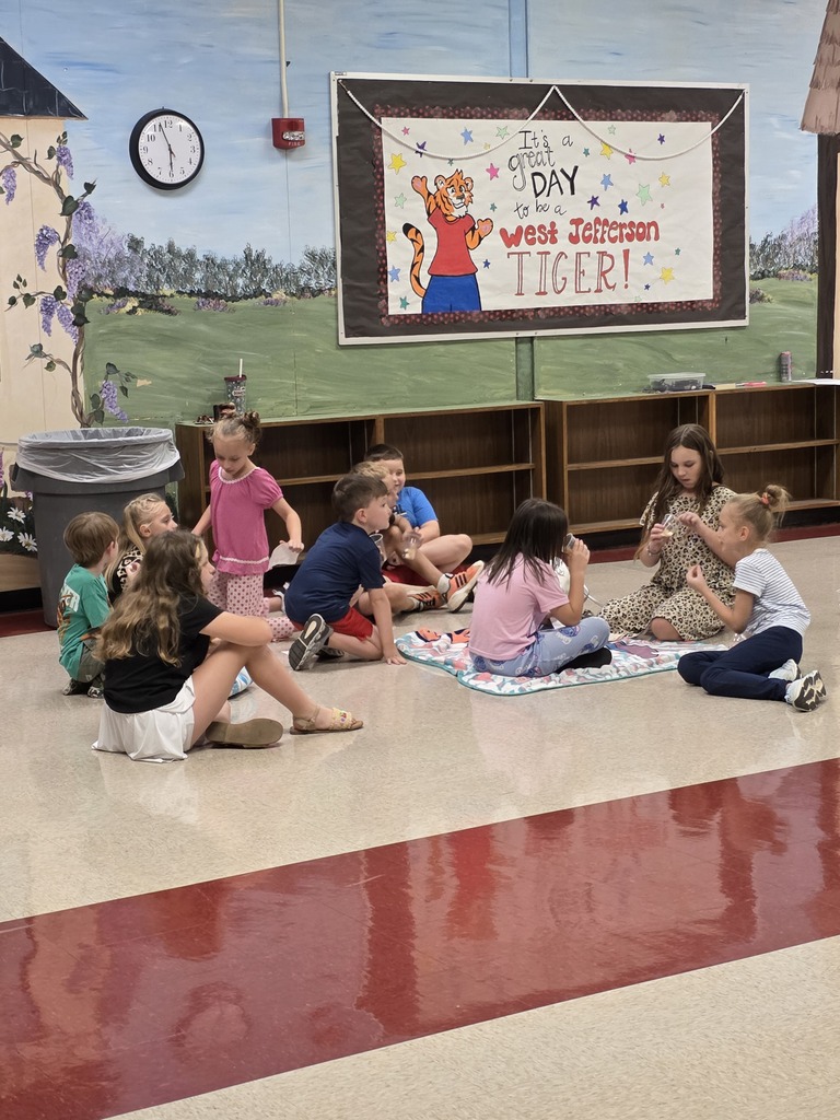 more students sitting on the floor eating a snack