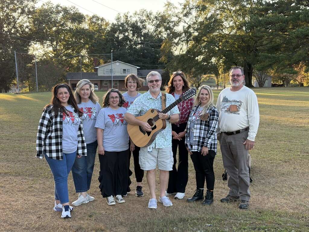 group of teachers standing around man with guitar
