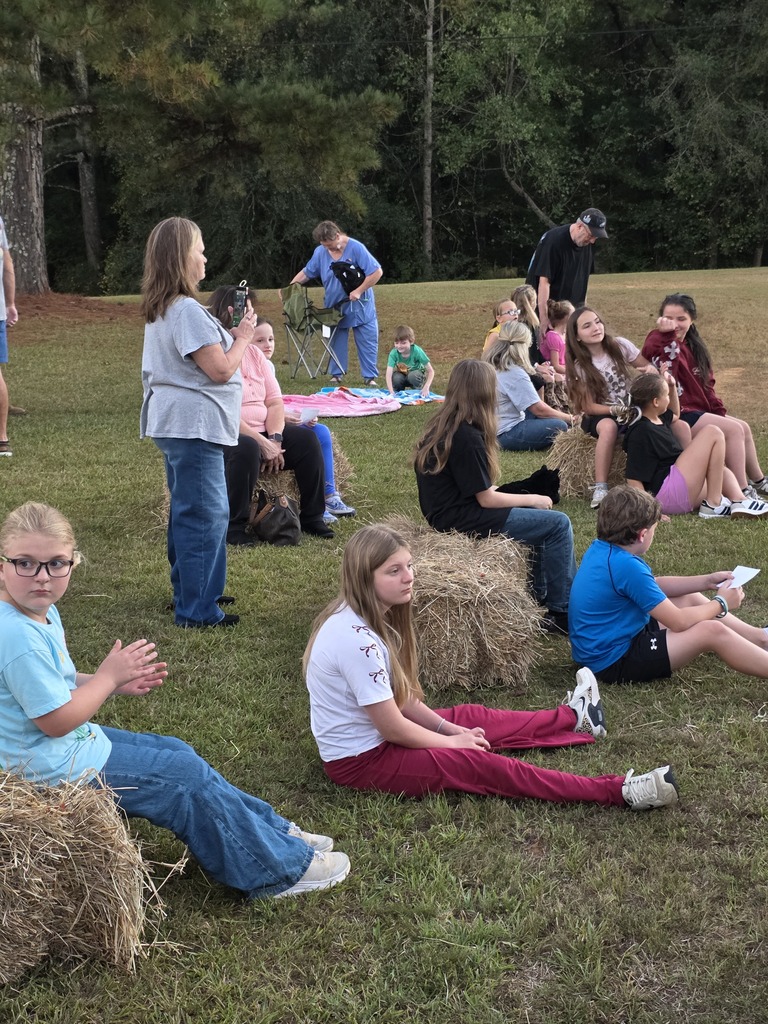 people sitting on bales of hay and blankets outside