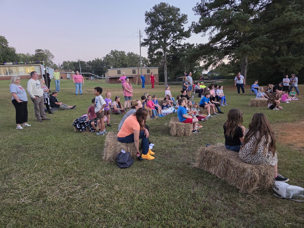 people sitting on bales of hay and blankets outside