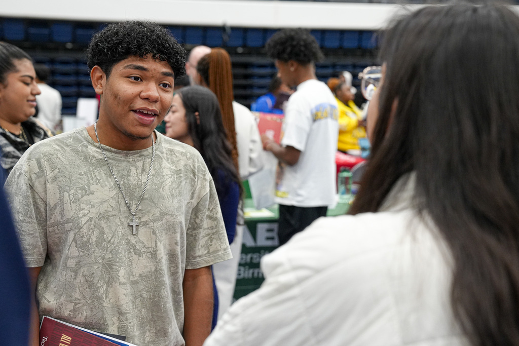 A student speaks to a recruiter during a college fair being held inside a gym.