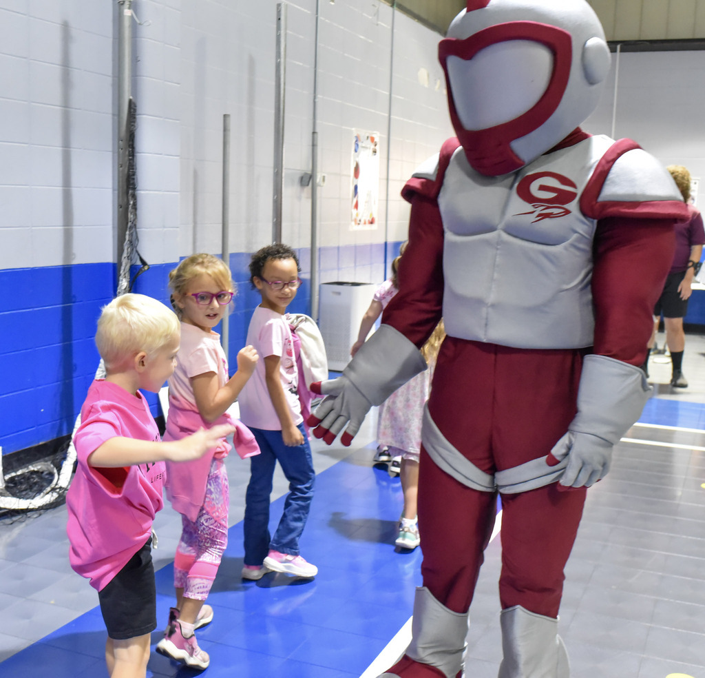 Rocket mascot shaking hands with kindergartener