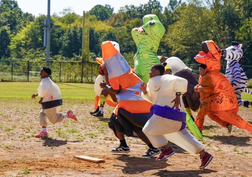 People wearing inflatable costumes run down a baseball field.