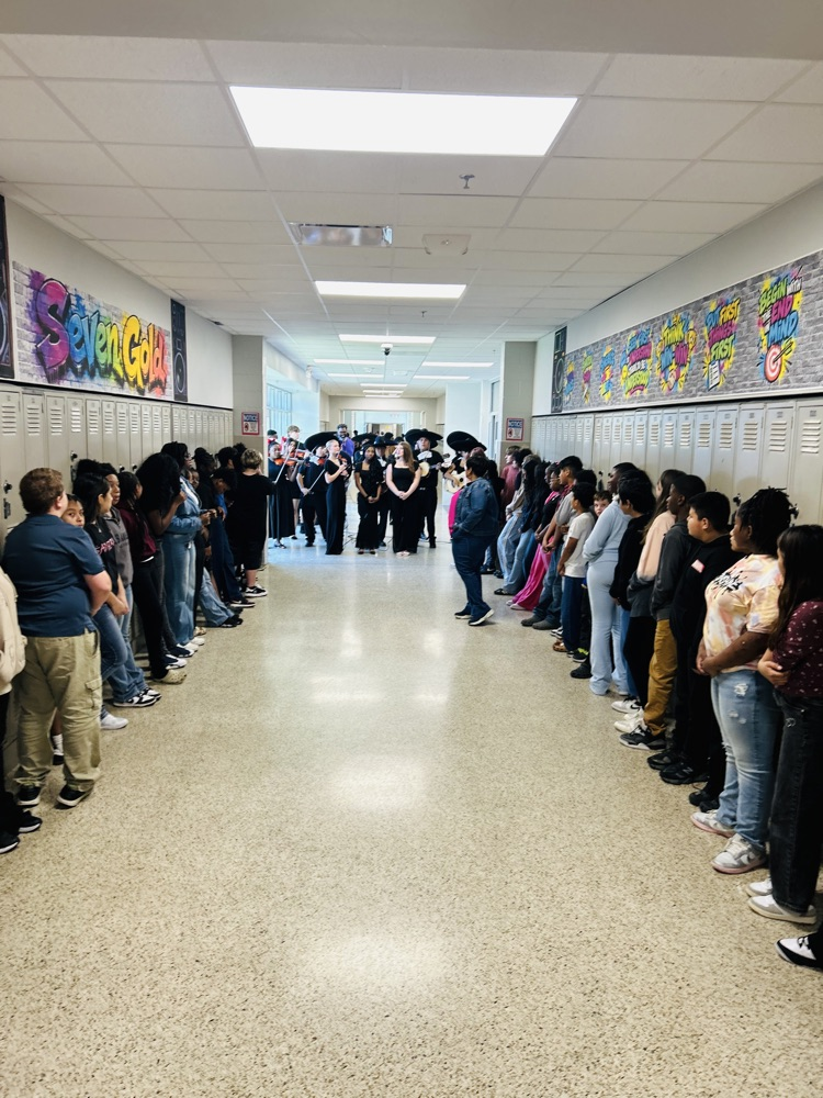HMS students line both sides of a hallway as visiting mariachi musicians perform in the center.