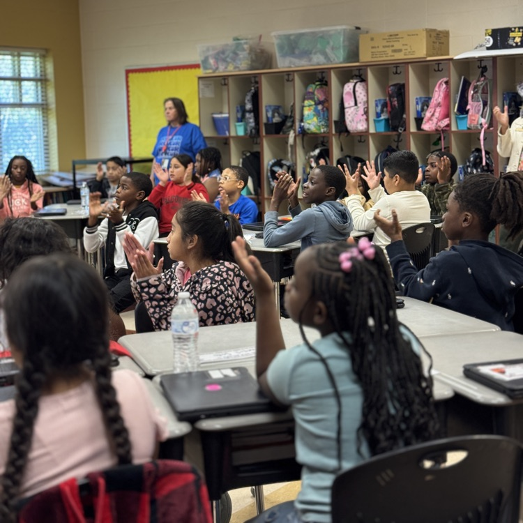 classroom filled with students sitting at their desk listening to the teacher