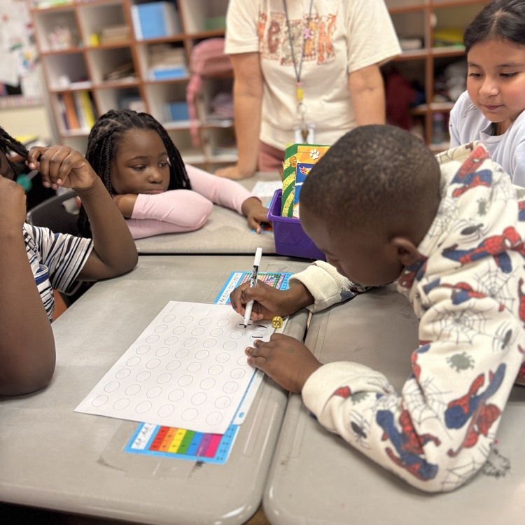 four students working in a group as one student writes on a papee