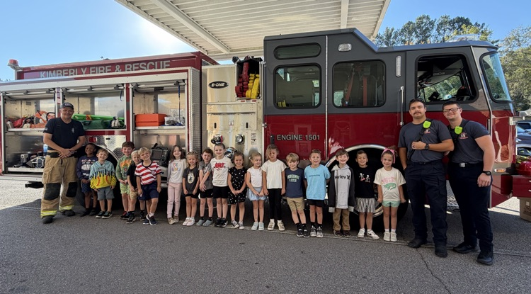 Kindergarten students and firemen beside the fire truck 