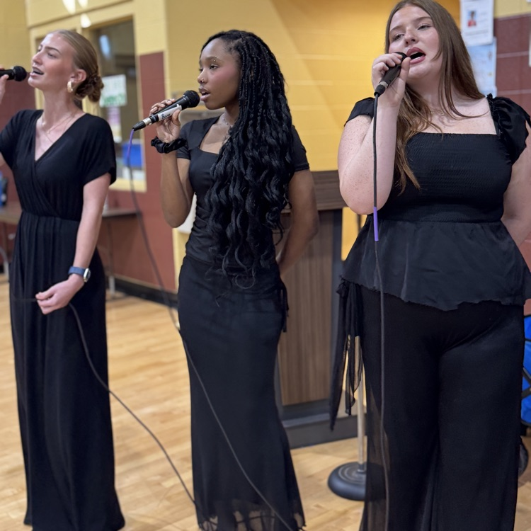 three hitls dressed in black and holding microphones singing