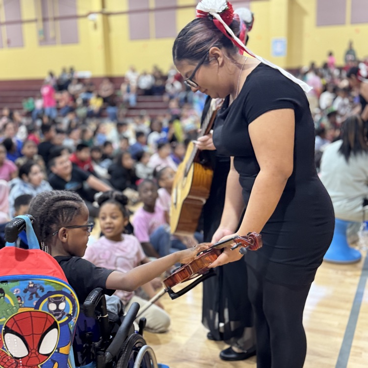a mariachi band member sharing her instrumental with a student in a wheelchair