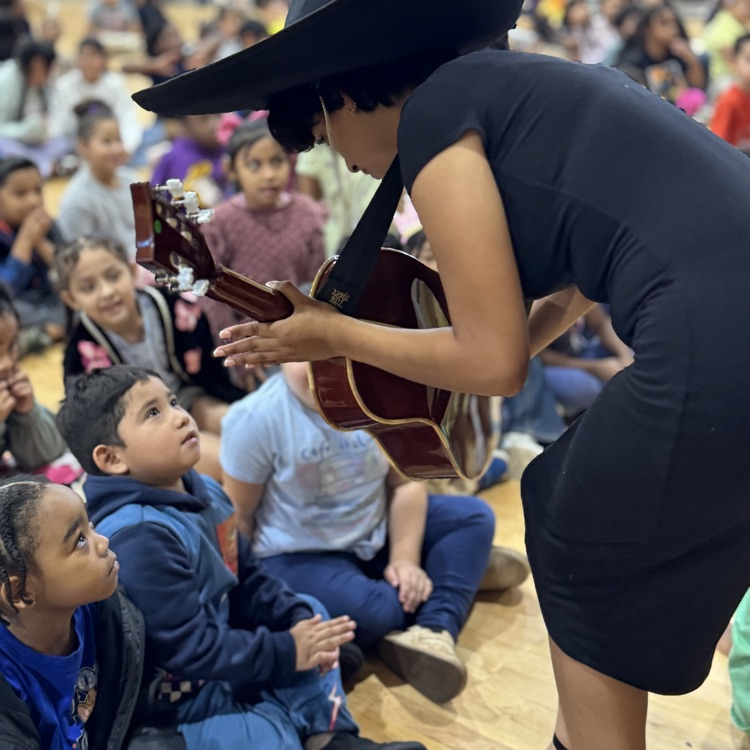 students looking at a band member with a stringed instrument