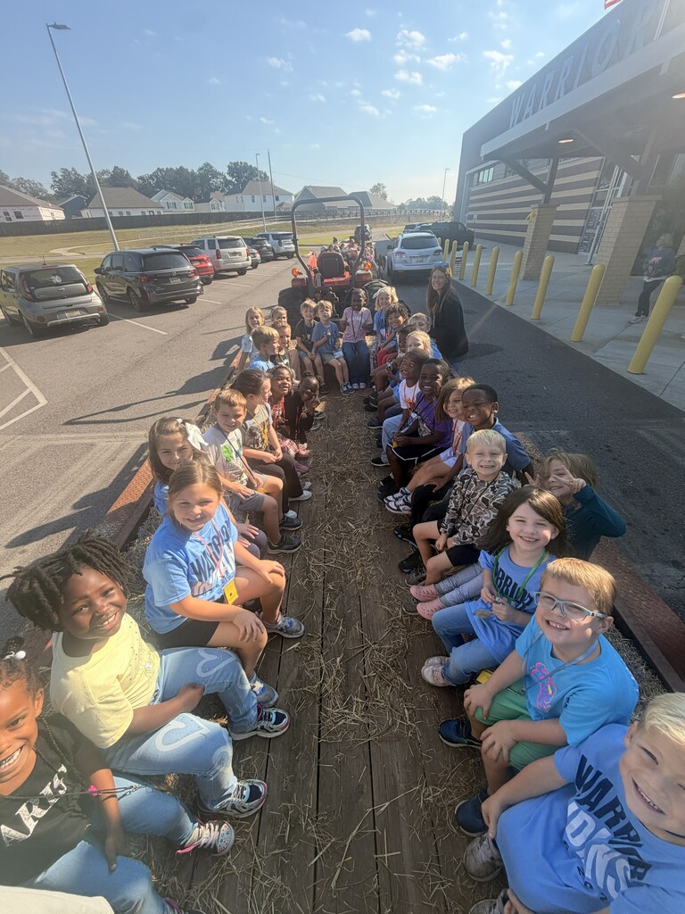 Students sitting on hay bales on the trailer getting ready to go on a hay ride 