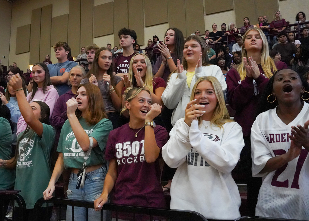 Students cheer while standing in the bleachers during a pep rally.