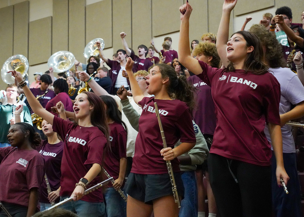 Band members do a chant while holding instruments during a performance at a pep rally.