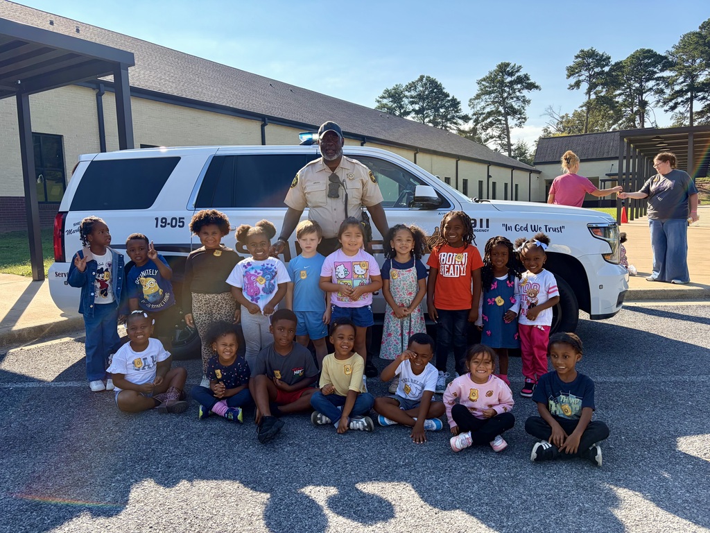 a group of students standing with our SRO by his police car smiling for a picture