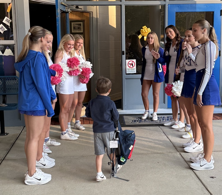 cheerleaders and dancers smiling in a student as they enter the school