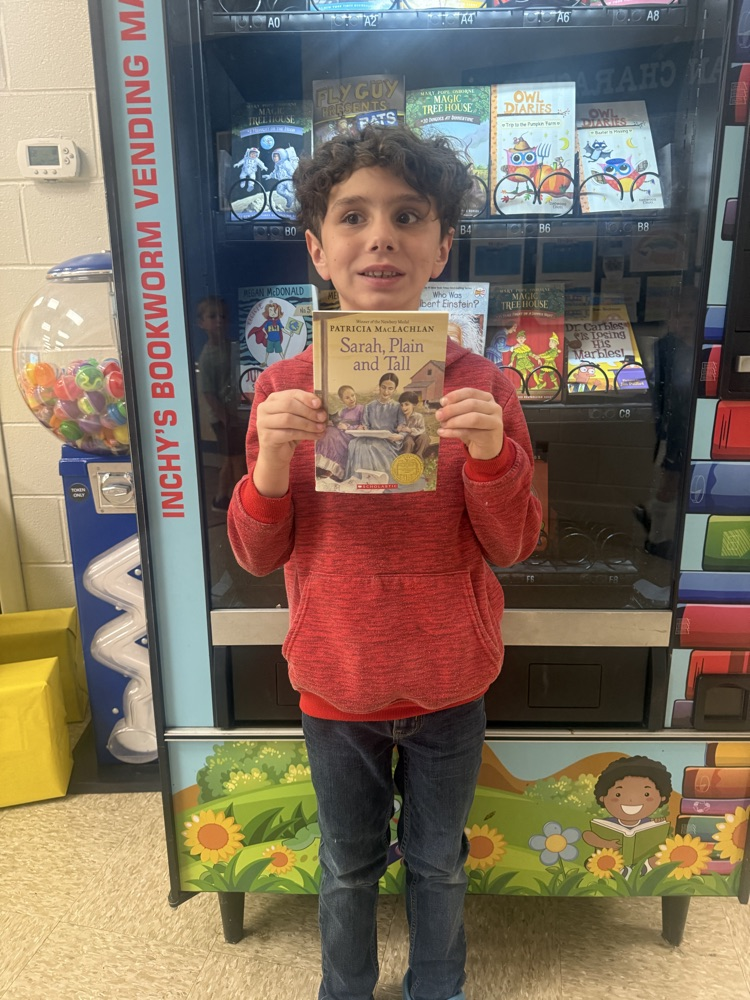 Young boy, smiling, and holding a book