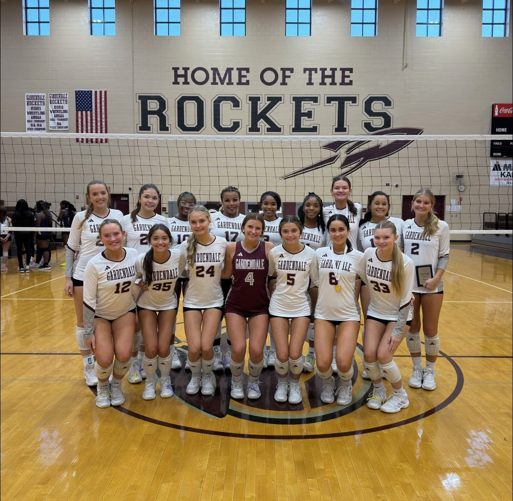 Gardendale High School volleyball players pose for a photo inside a school gym.