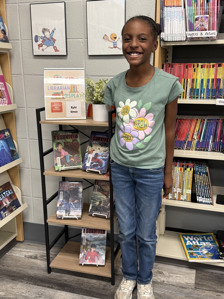 picture of a student posing in front of books in the library