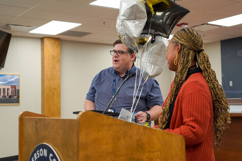 Paul Kelsey speaks after receiving balloons from a woman in the JEFCOED Board Room.