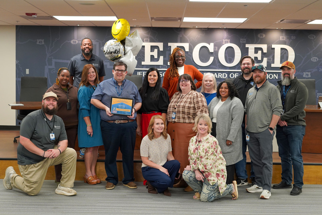 JEFCOED's IT department members stand and kneel in the JEFCOED Board Room for a photo.