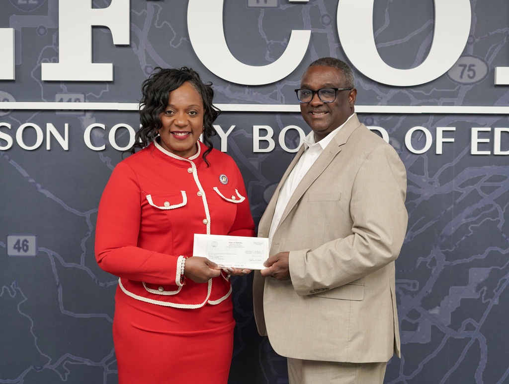 Senator Merika Coleman and Superintendent Dr. Walter Gonsoulin pose for a photo in the JEFCOED conference room. They hold a check in their hands.