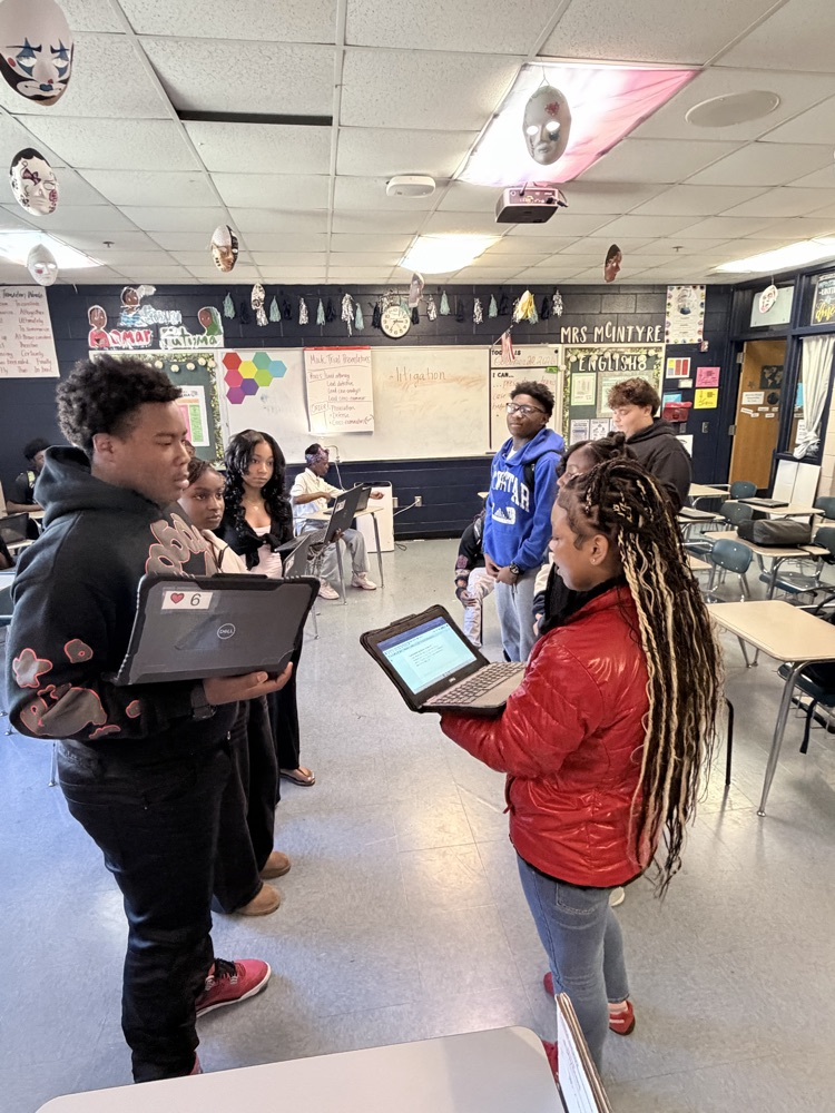 Students holding computers debating