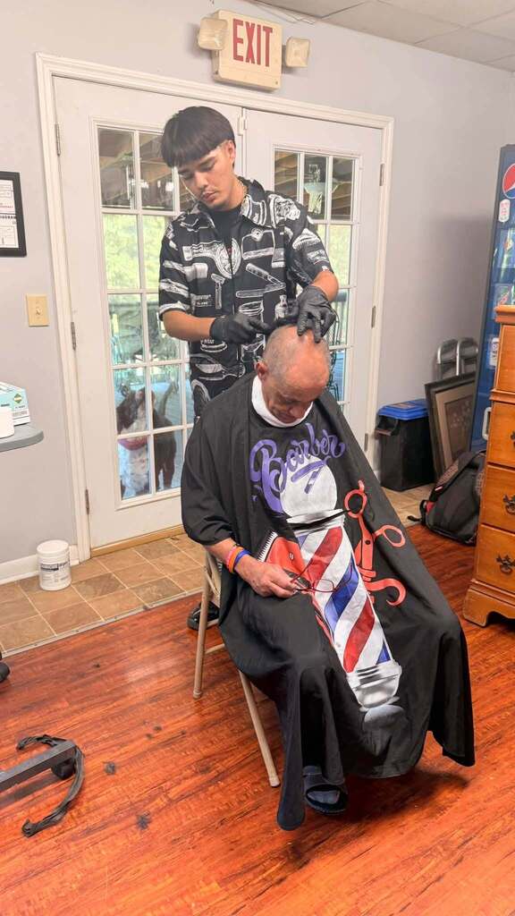 A student trims a man's hair.