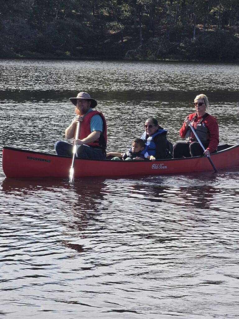 2 people sitting in the middle of a canoe while 2 others paddle the canoe