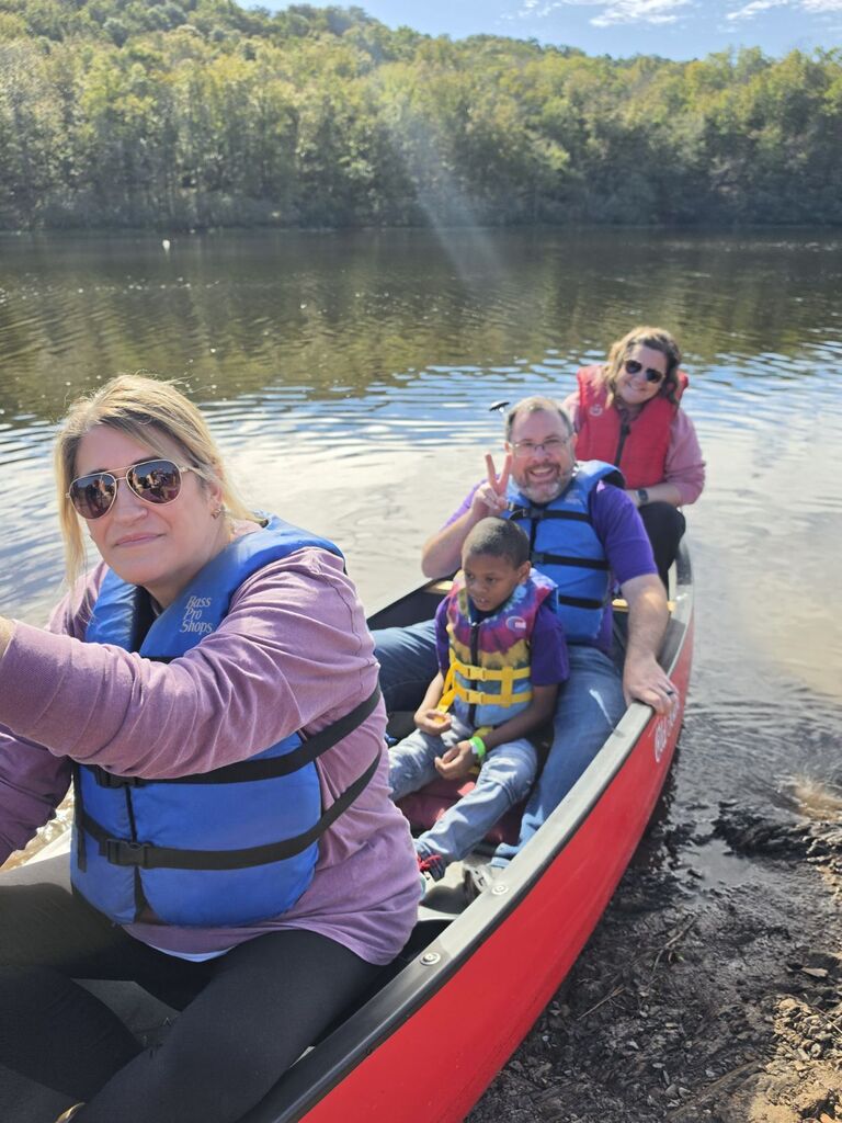 4 people in a canoe at the edge of the lake about to push off